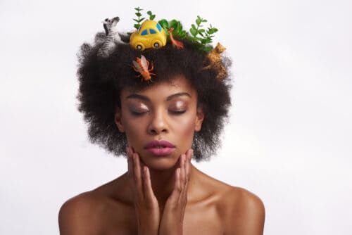 Olhar de moda e natureza humana. Feche o retrato de uma mulher afro-americana pacífica em penteado safari, fechando os olhos enquanto ternamente toca seu rosto. Isolado em números de anjos brancos