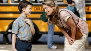 Serie de televisión Young Sheldon: Una mujer se inclina para hablar con un niño frente a un autobús escolar; la mujer parece melancólica.