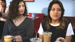 SKAM Austin-serien: To teenagepiger sidder på en kaffebar; den ene ser sardonisk på den anden.