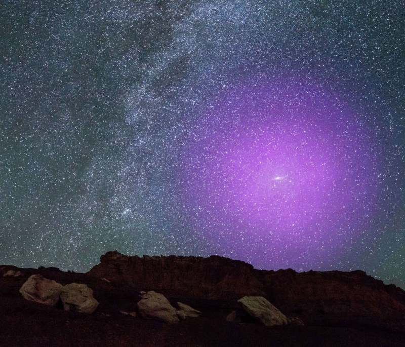 Mākslas darbs, kas attēlo Andromedas galaktikas oreolu (purpursarkanā krāsā), kas uzlikts uz nakts debesu attēla, lai parādītu tā mērogu. Pateicība: NASA, ESA, J. DePasquale un E. Wheatley (STScI) un Z. Levay