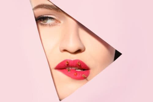 Vista de mulher jovem e bonita com maquiagem criativa nos lábios através de recorte em papel colorido