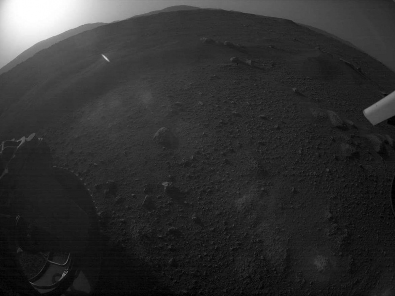 Първият залез на Perseverance беше забелязан от една от камерите за избягване на опасности на първия му сол на Марс (блясъкът в горния ляв ъгъл е Слънцето). Камерата използва обектив с рибешко око, изкривяващ перспективата. Кредит: НАСА/JPL-Caltech