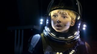 سلسلة Lost in Space: يقف صبي يرتدي زيًا فضائيًا وخوذة أمام خلفية مظلمة ؛ يبدو مضطربًا وخائفًا.