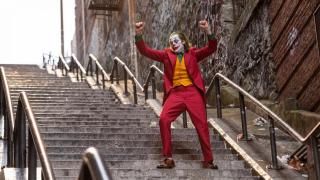 „Joker“ filmas: Joaquinas Phoenixas kaip „Joker“, pakėlęs rankas laiptinėje