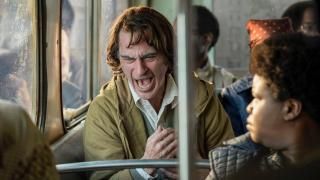Joker-film: Arthur Fleck griner i en bus, mens andre passagerer ser på